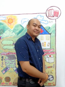 Khammouane stands in front of World Education Laos mural